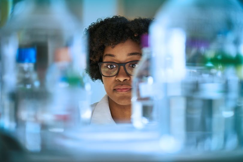 A female researcher is framed by lab equipment